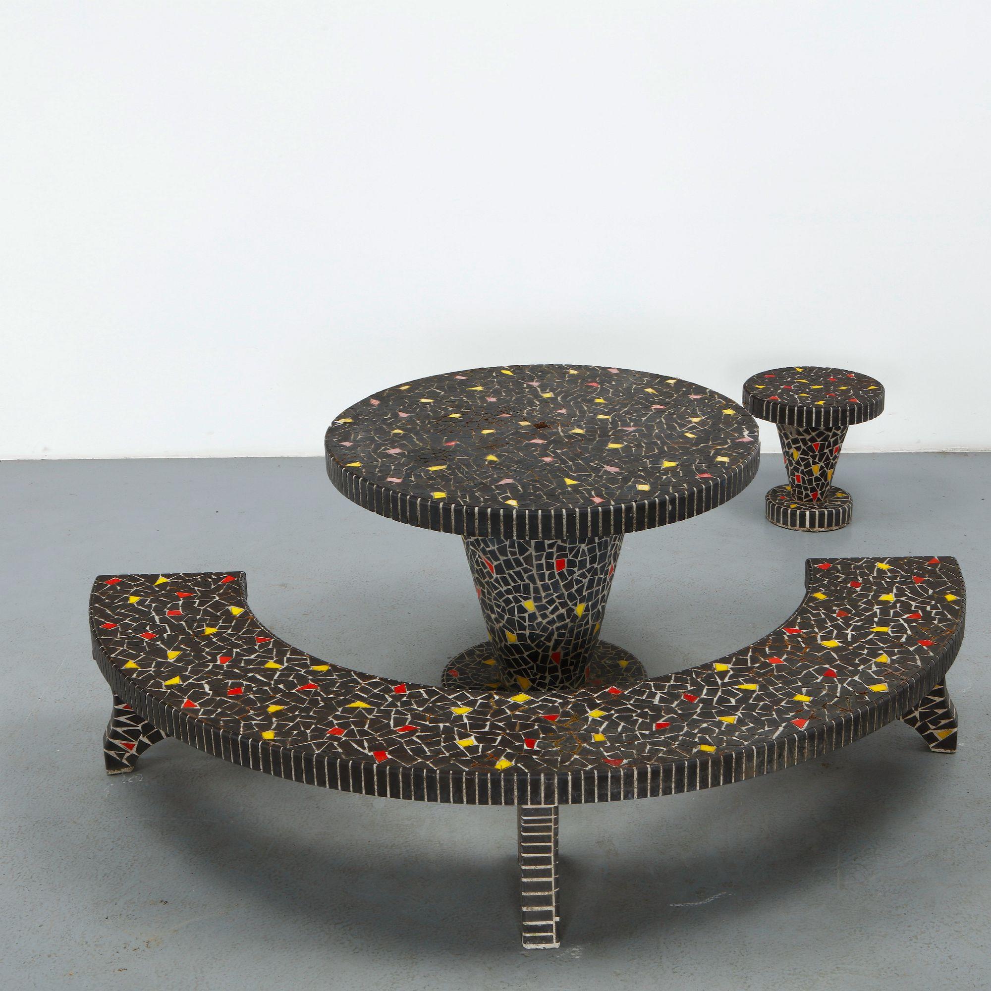Black mosaic dining set with a round tiled table, curved bench and stool accented with yellow and red tile shards